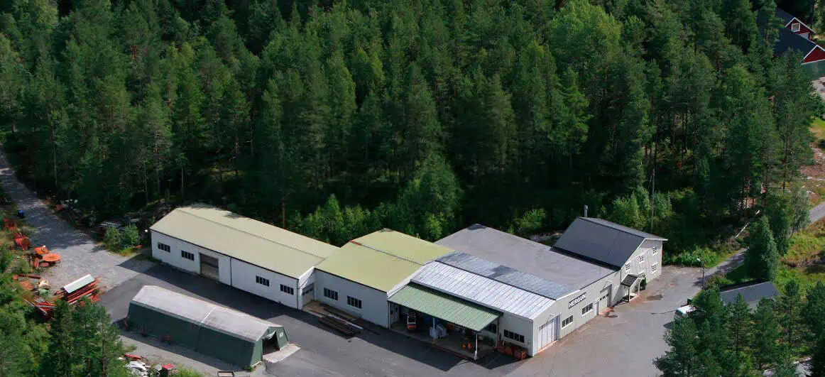 Luftfoto av Hergun Sveiseindustri sitt verksted på Espelandsmyr i Vegårshei, med HERGUN-logo på veggen og skog rundt